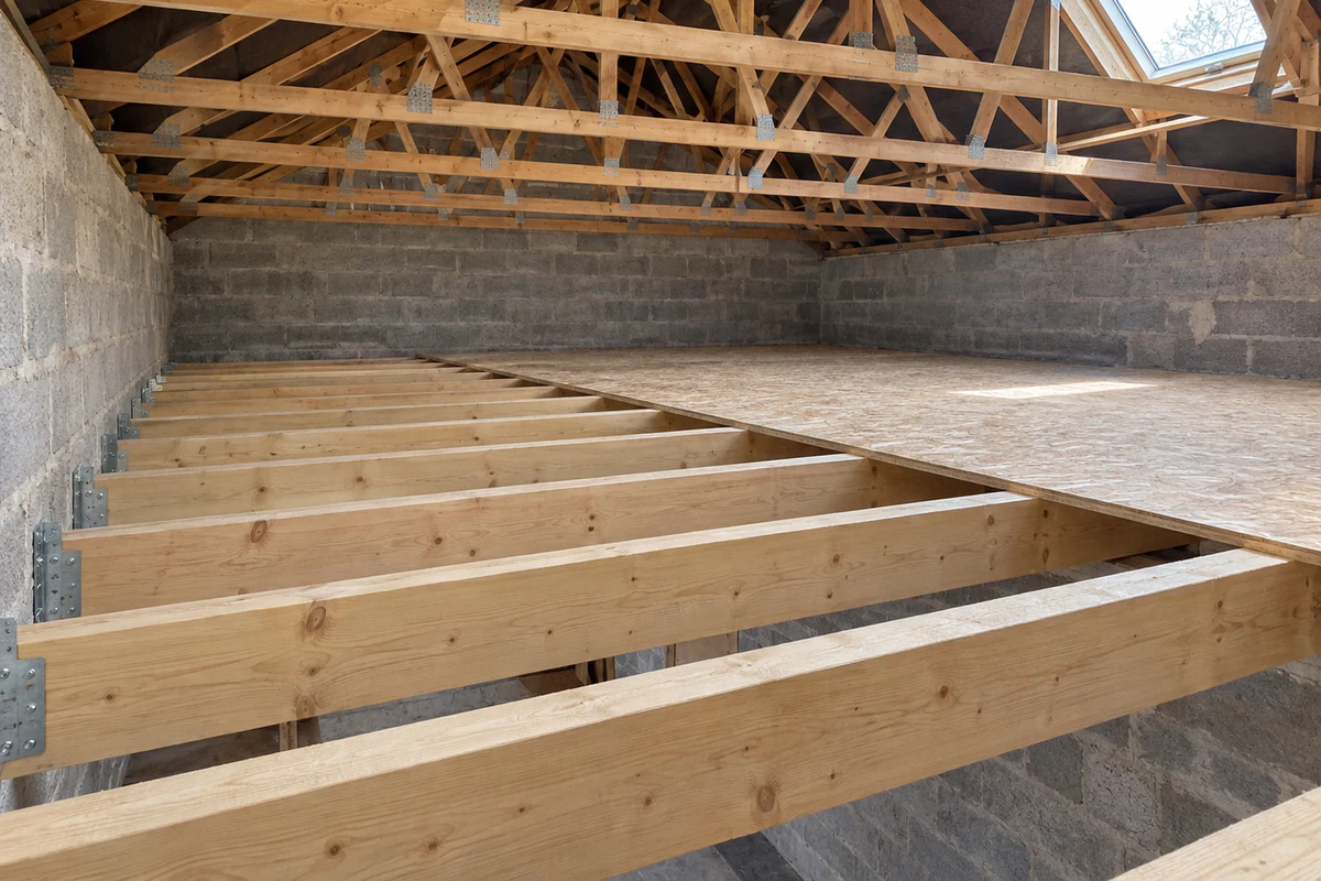 Solivage neuf en bois massif posé sur les murs porteurs d'un comble, indépendant des entraits de la charpente existante visible au-dessus, chantier sans personne