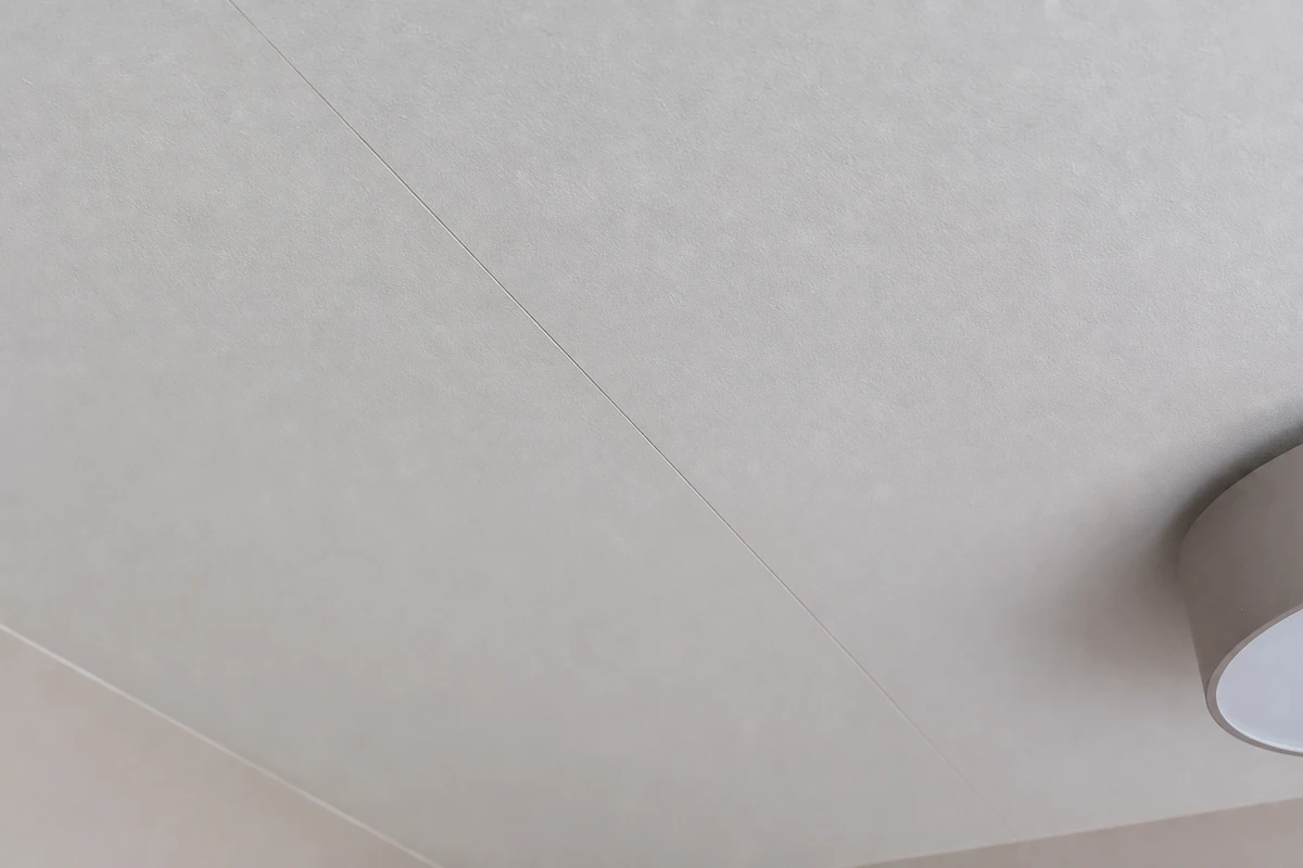 Fissure fine suivant un joint de plaques de plâtre au plafond d'une pièce lumineuse