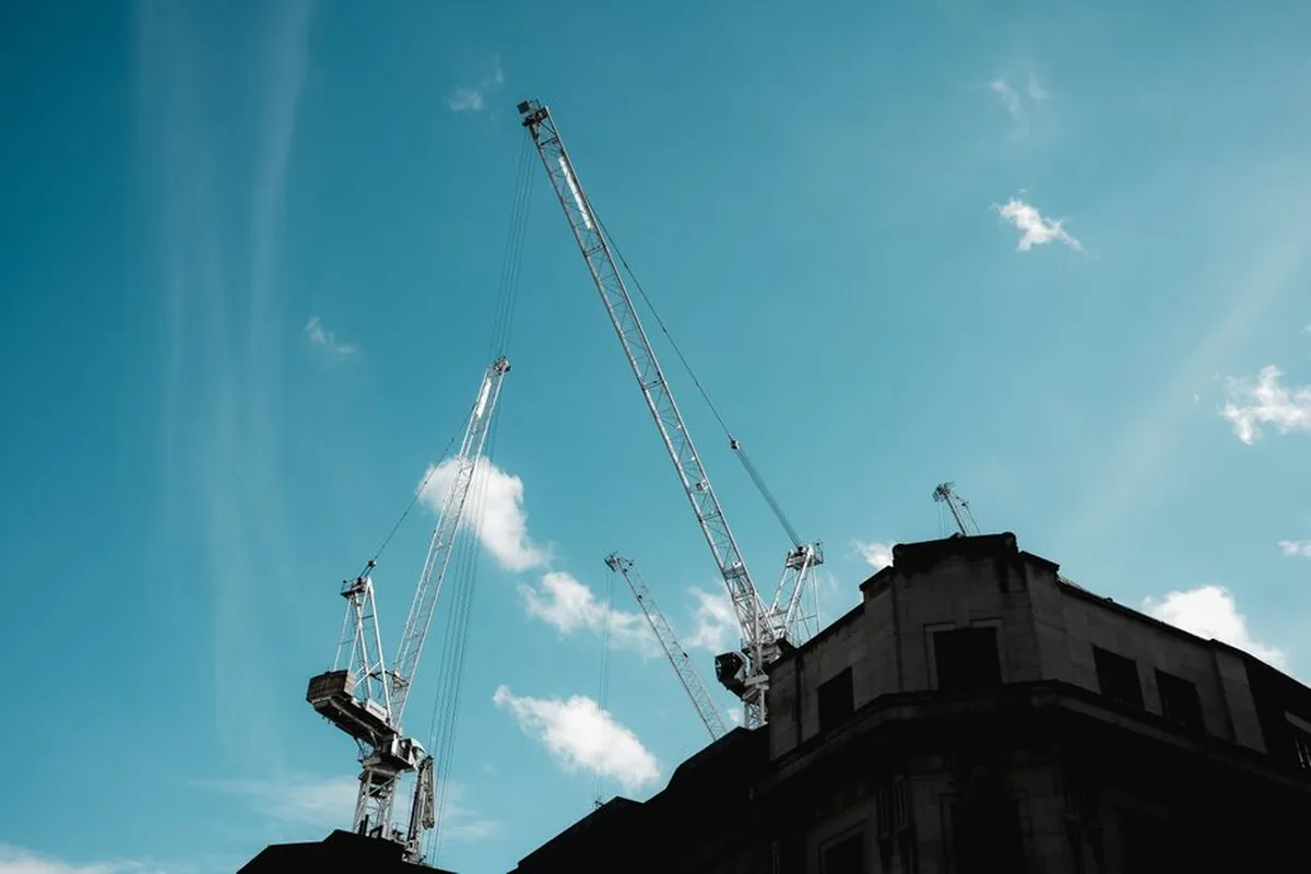 Grues de chantier près d'un immeuble, illustrant les travaux à proximité pouvant provoquer des fissures