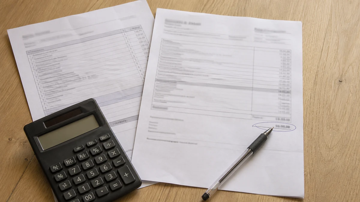 Lettre d'offre d'indemnisation d'assurance posée sur une table à côté d'un devis de réparation de fissure et d'une calculatrice, un stylo posé sur le montant net entouré
