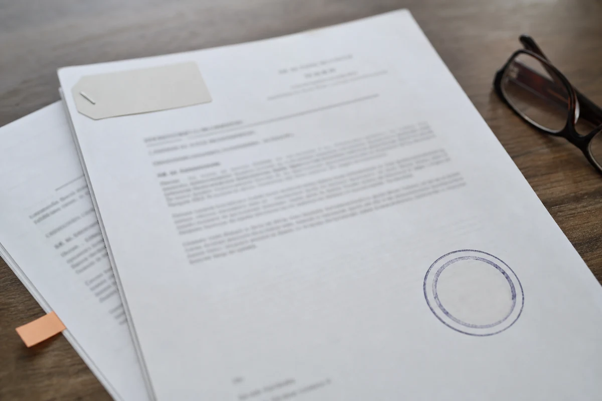 Deux décisions de justice imprimées superposées avec un cachet rond tamponné à l'encre, une étiquette de référence agrafée et des lunettes de lecture posées à côté