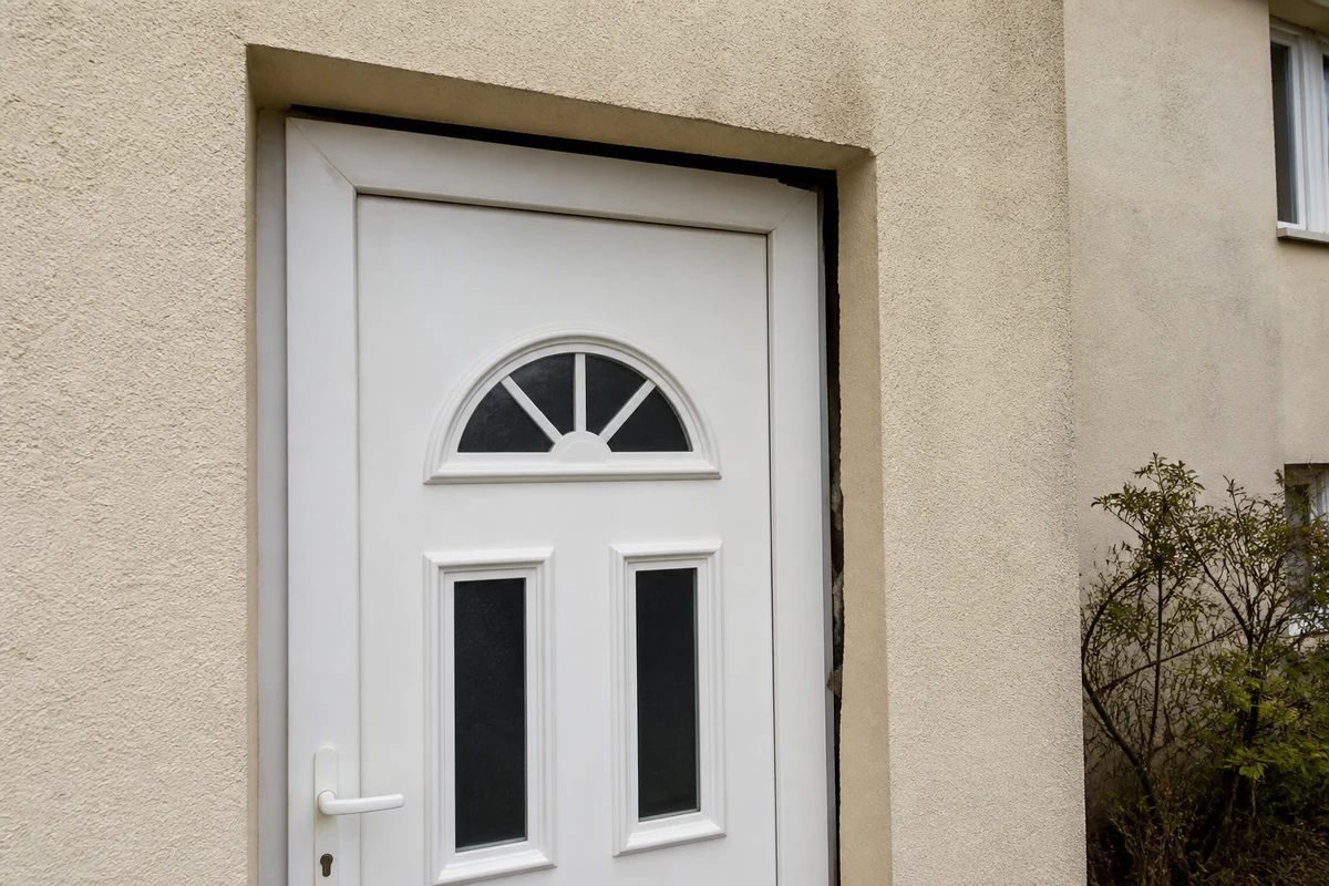 Cadre de porte extérieure désaligné avec un écart visible entre l'huisserie et le mur, signe d'un affaissement du bâti