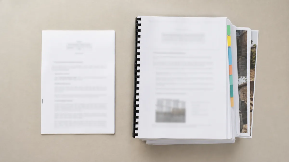 Deux documents posés côte à côte sur un bureau, à gauche un courrier de deux pages agrafé, à droite un rapport d'expertise relié de plusieurs dizaines de pages avec onglets de couleur et annexes photographiques dépassant, aucune personne dans le cadre