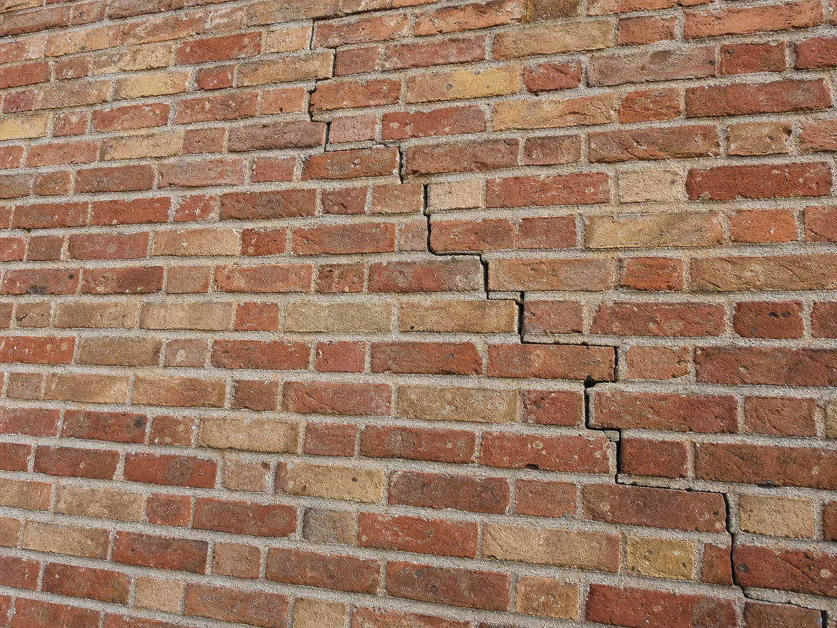 Fissure en escalier non traitée sur un mur en brique ou pierre, avant intervention