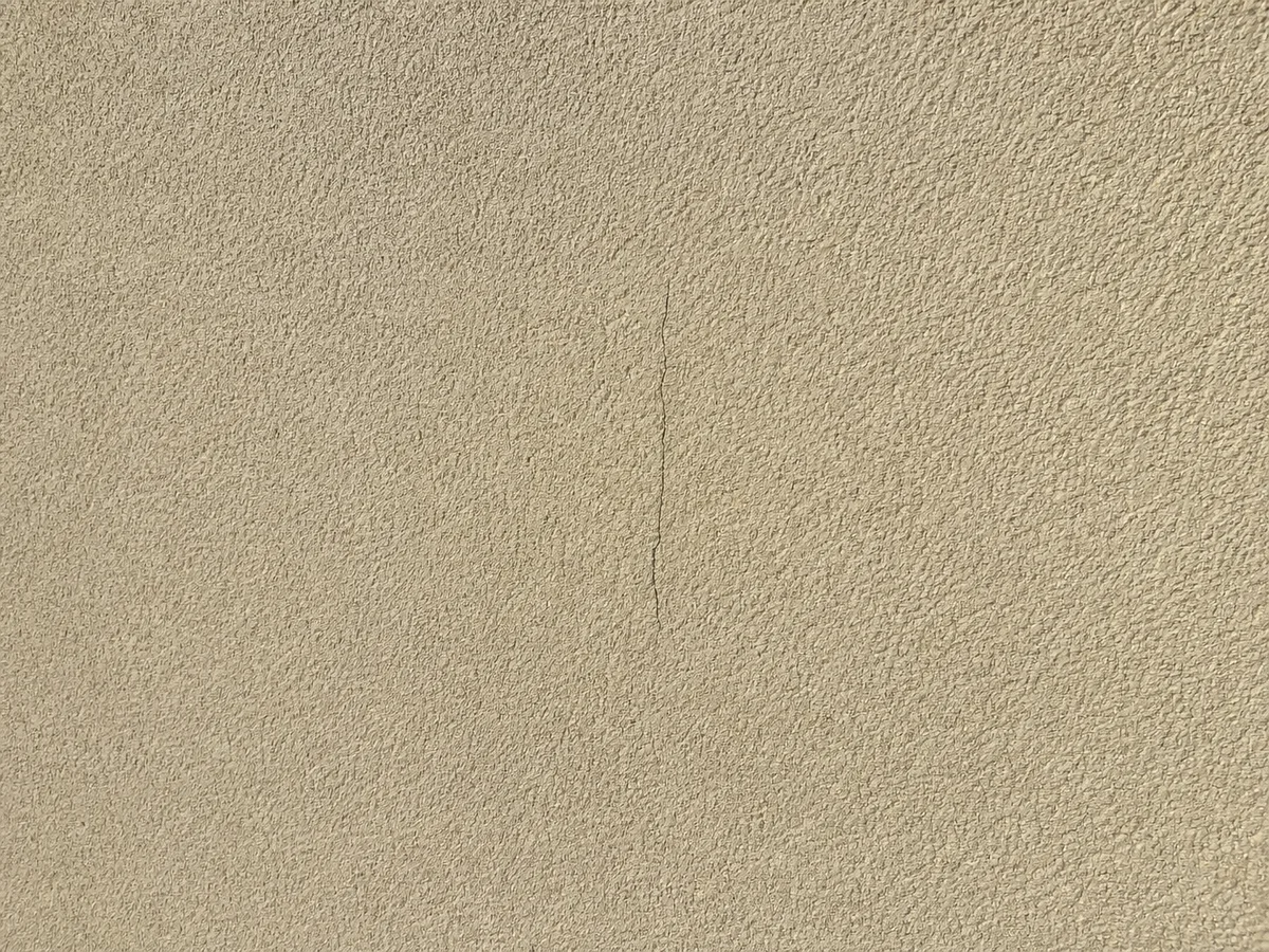 Fissure fine non traitée sur un mur enduit clair, avant intervention