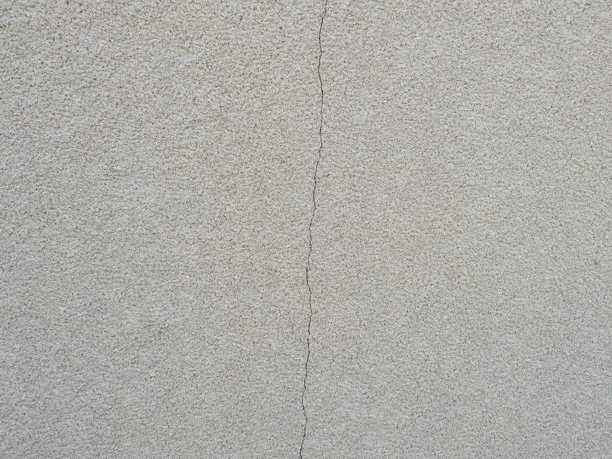Fissure de façade non traitée de 2 à 3 mm sur un mur enduit clair, avant intervention