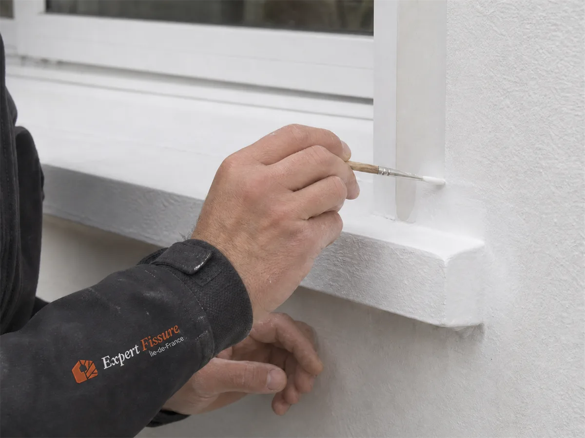 Expert Expert Fissure Île-de-France appliquant au pinceau la finition de peinture réfléchissante sur les rebords d'une façade